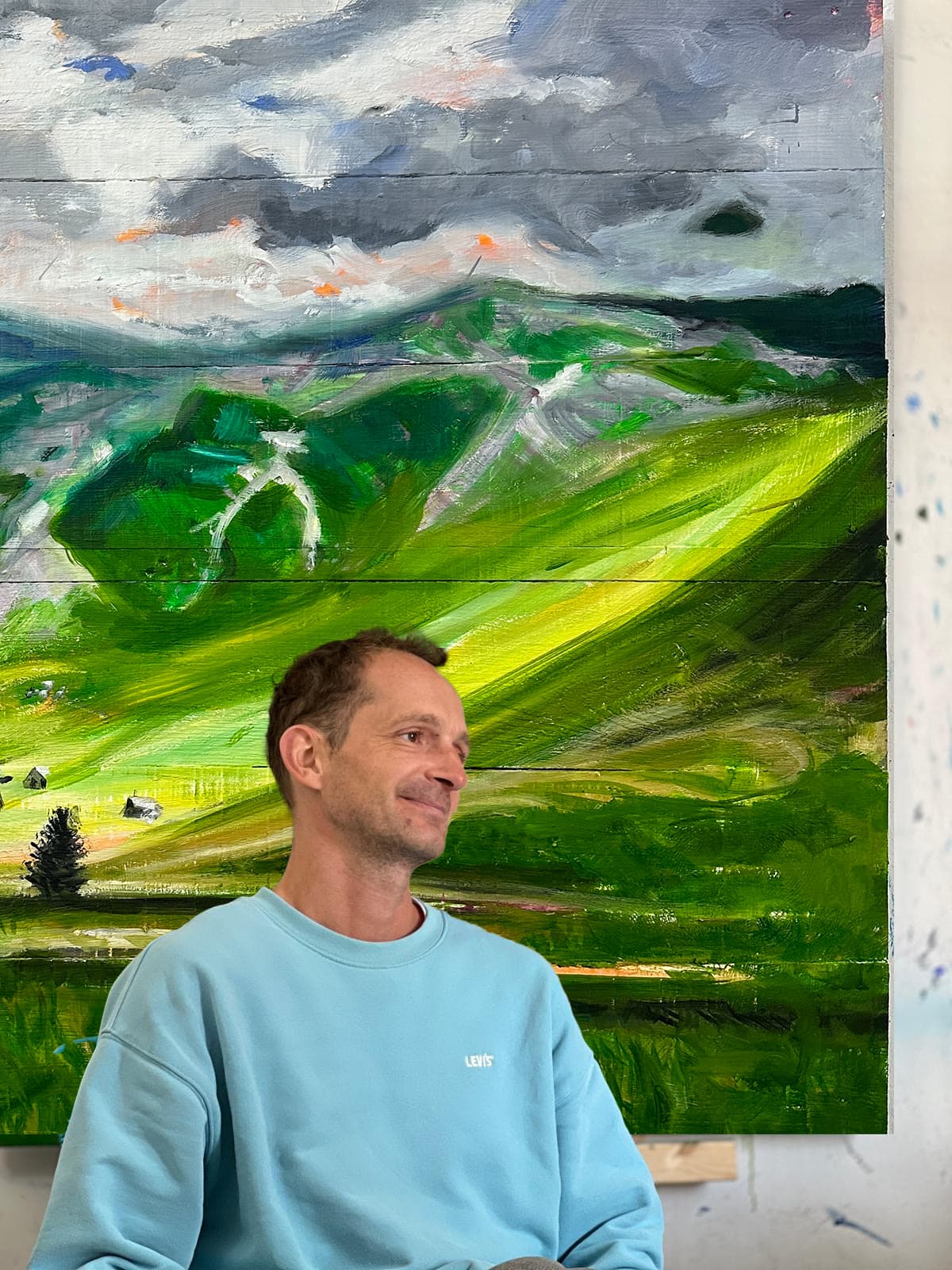 künstler nikolaus kriese im atelier für auftragsmalerei vor einer Landschaftsmalerei